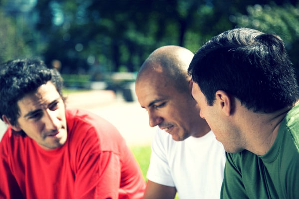 Three young men talking outdoors